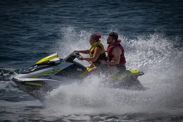 Couple riding a jet ski at speed and throwing up spray on the open sea