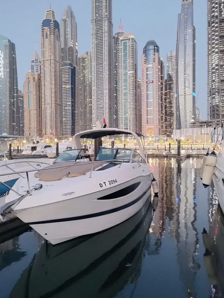 Luxury yacht at dusk with the Dubai skyline glowing behind it