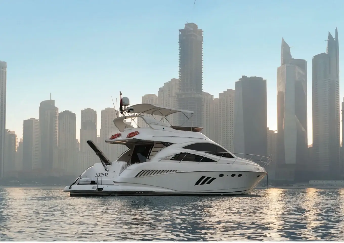 Luxury motor yacht cruising past the Dubai Marina skyline at golden hour